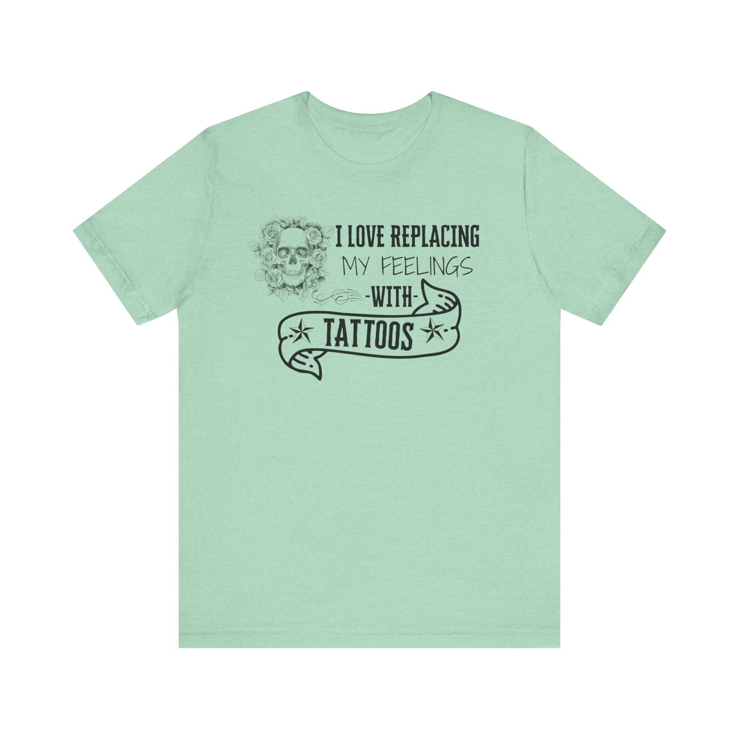 A sarcastic graphic tee stating 'I love replacing my feelings with tattoos' in color heather mint