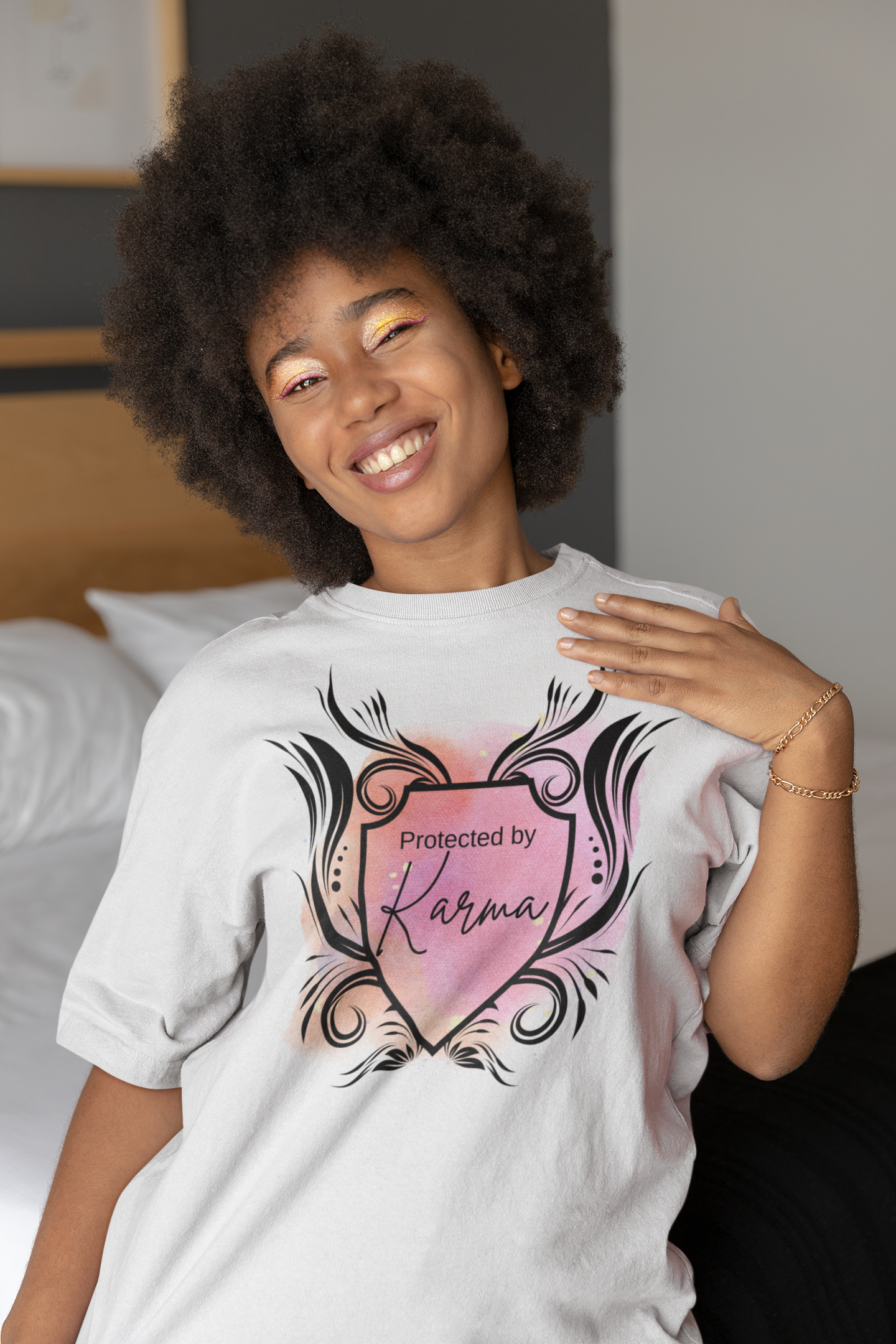 Woman with beautiful afro and smile wearing graphic tee stating Protected By Karma in color white