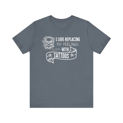 A sarcastic graphic tee stating 'I love replacing my feelings with tattoos' in color steel blue