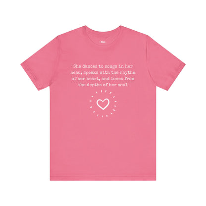 Comfortable good vibes graphic t-shirt stating 'She dances to songs in her head, speaks with the rhythm of her heart, and loves from the depths of her soul' in color charity pink