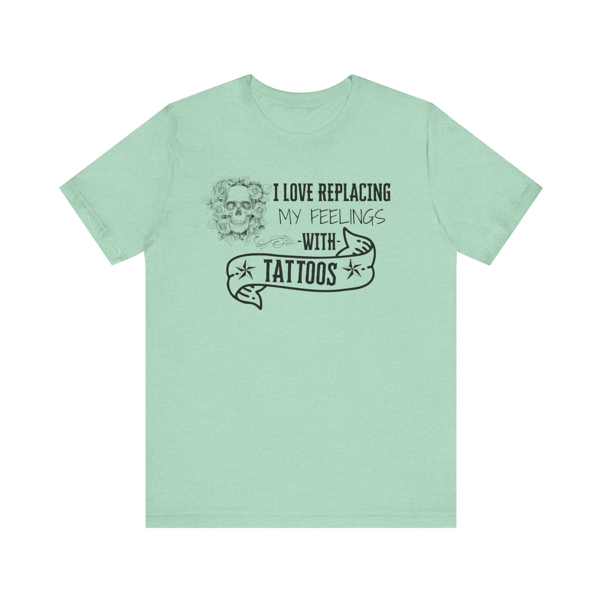 A sarcastic graphic tee stating 'I love replacing my feelings with tattoos' in color heather mint