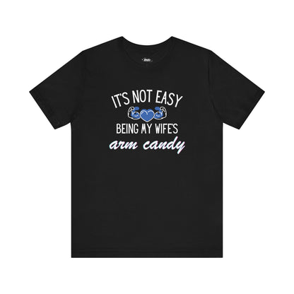 Graphic tee stating It's Not Easy Being My Wife's Arm Candy in color black