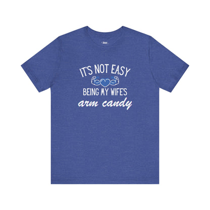 Graphic tee stating It's Not Easy Being My Wife's Arm Candy in color true royal heather