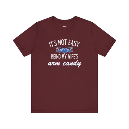 Graphic tee stating It's Not Easy Being My Wife's Arm Candy in color maroon