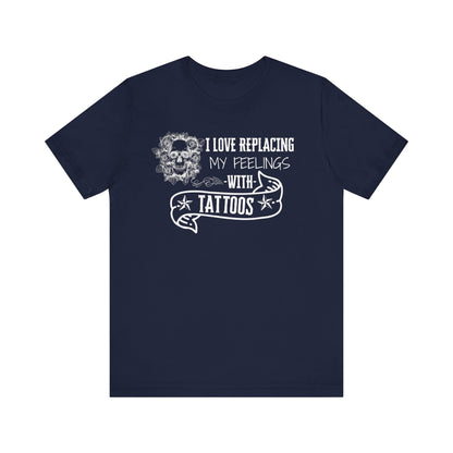 A sarcastic graphic tee stating 'I love replacing my feelings with tattoos' in color navy