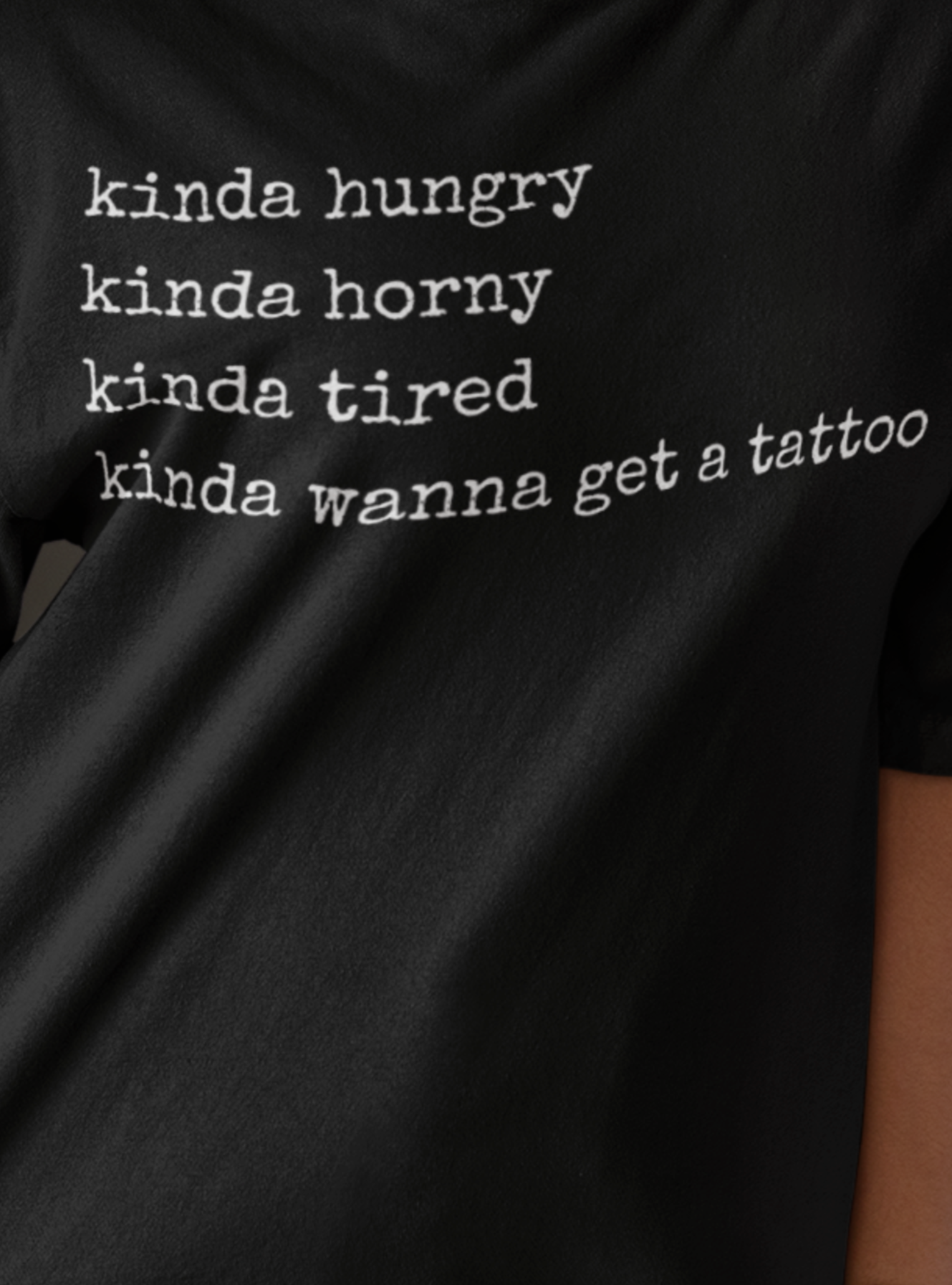 woman wearing adult humor oversized graphic t-shirt stating 'Kinda hungry. Kinda horny. Kinda tired. Kinda wanna get a tattoo" in color black